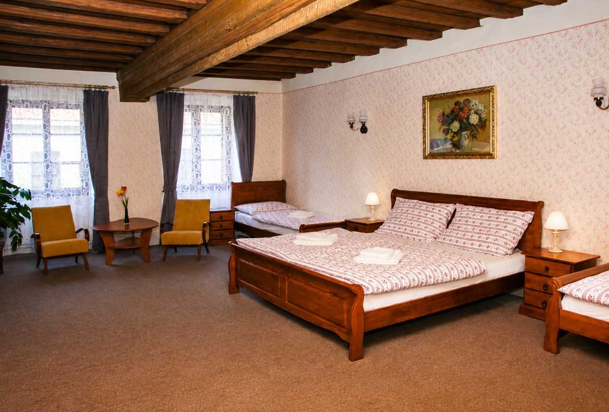 Spacious room at Mini Hotel Abraka with wooden furniture and floral bedding in the old town of Český Krumlov